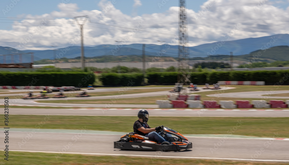 black and silver helmet driver driving a kart on a circuit