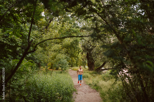 Handsome fitness caucasian man in shorts trains and runs in the forest. Fitness in nature