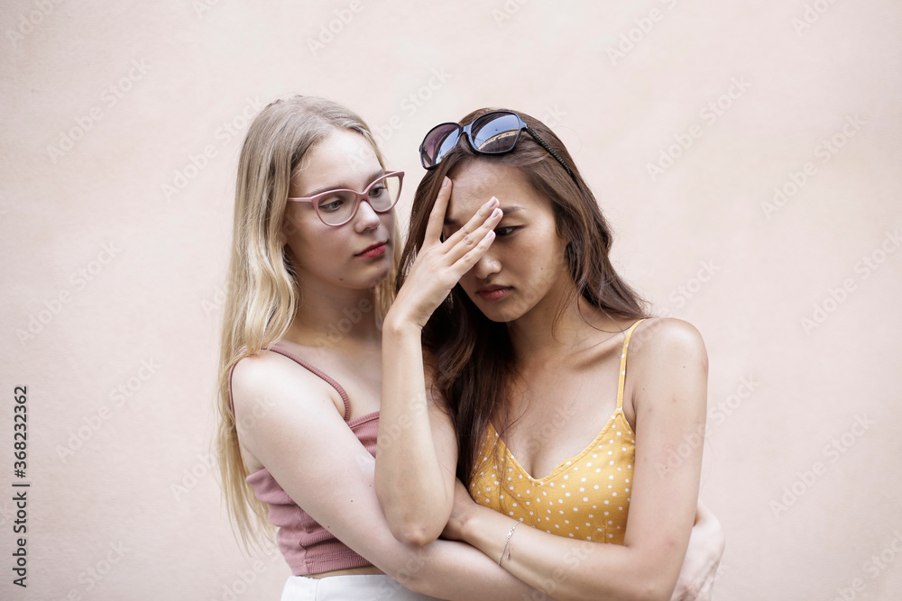 Two girls in front of a pink background Two girls in front of a pink background
