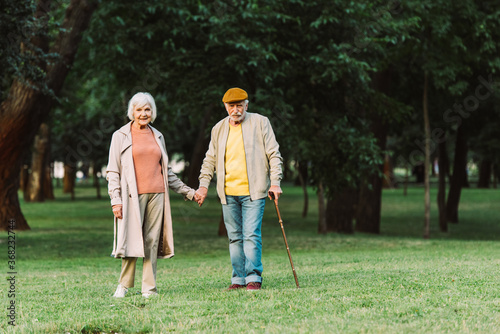 Smiling elderly woman holding hand of husband in park