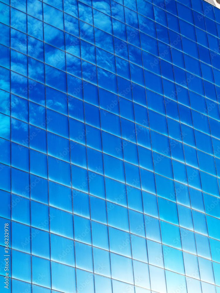 Background clouds reflected in the windows of a modern building on the sunset at the end of the day Background clouds reflected in the windows of a modern building on the sunset at the end of the day