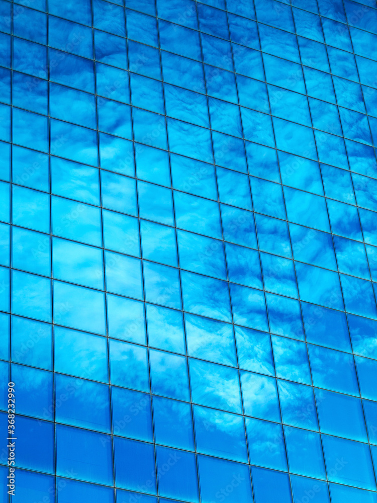 Background clouds reflected in the windows of a modern building on the sunset at the end of the day Background clouds reflected in the windows of a modern building on the sunset at the end of the day