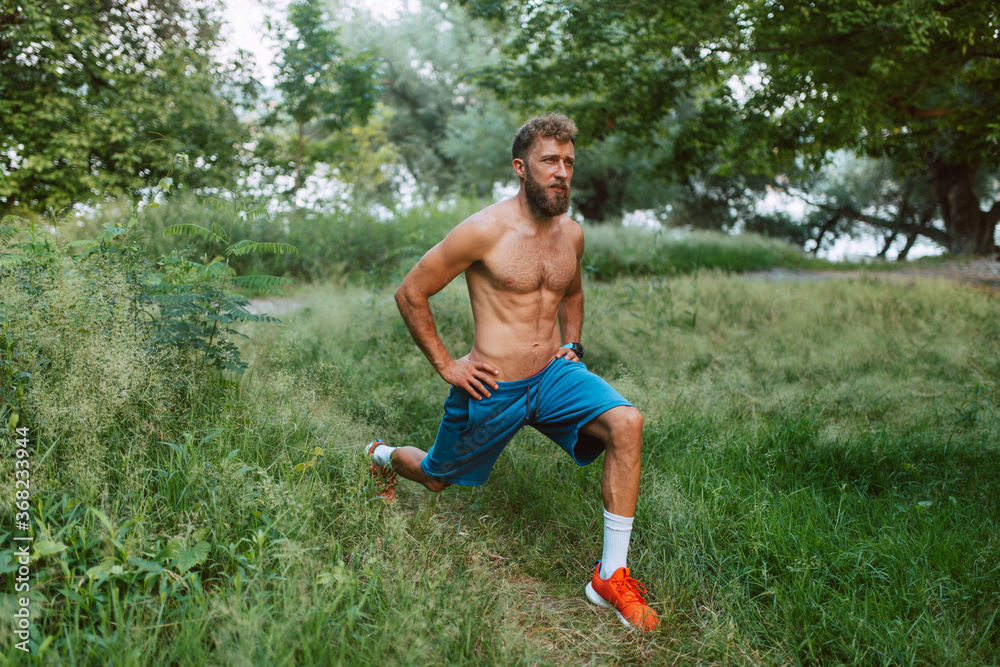 Sport fitness caucasian man with bare-chested trains and does exercises in the forest. Step exercise Sport fitness caucasian man with bare-chested trains and does exercises in the forest. Step exercise