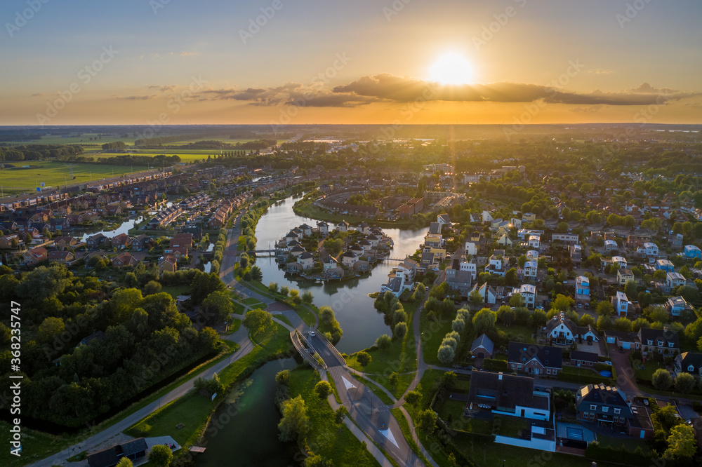 Typical Dutch residential area with houses located on the water. This is the Beuning pond (dutch: Beuningse plas). Made during sunset on a warm summer evening. Beuningen, gelderland, the netherlands.