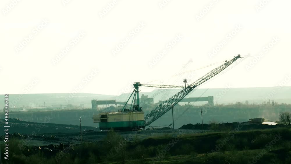 Ferrous metallurgy. The work of heavy machinery. Mining of iron ore. A huge bucket pours the rock. Industrial landscape. Ferrous metallurgy. The work of heavy machinery. Mining of iron ore. A huge bucket pours the rock. Industrial landscape.