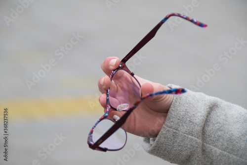 Close up of a woman's hand holding reading glasses out on a street. Negative space. Copy space for advertising. 