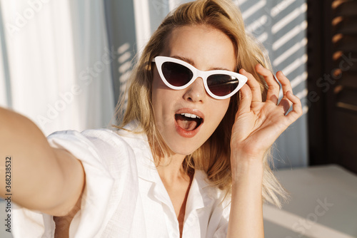 Image of seductive surprised woman in sunglasses taking selfie photo photo