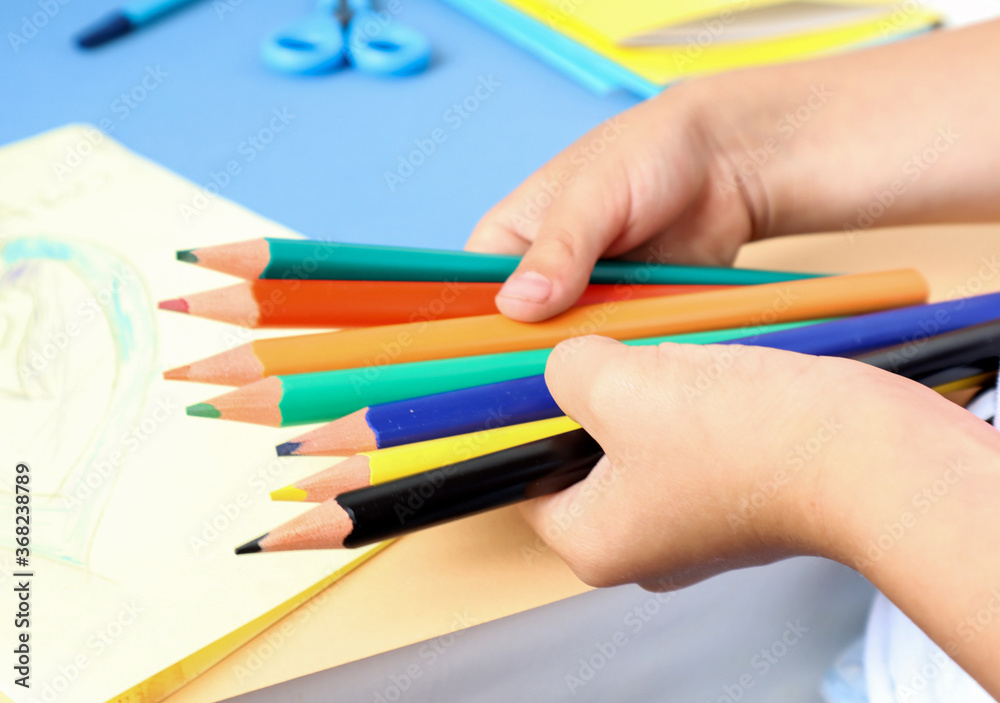 Colorful pencils in the hands of a child, side view, close-up Colorful pencils in the hands of a child, side view, close-up