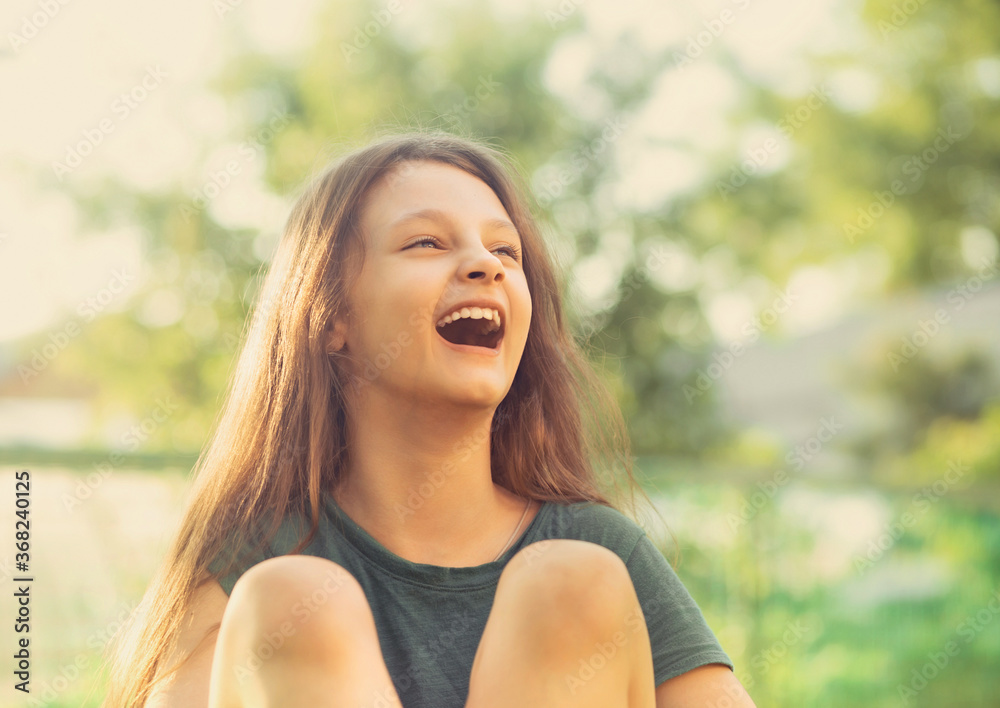 Happy smiling fun casual kid girl lying on the grass on nature summer background. Closeup Happy smiling fun casual kid girl lying on the grass on nature summer background. Closeup