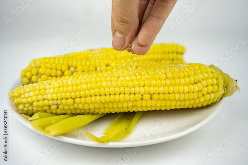 boiled sweet corn with salt on a white plate
