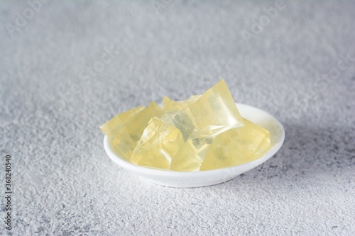 Gelatin, agar-agar, gelatinous mass (cubes in the form of crystals) on a gray background. Gelling agent (collagen) for culinary, confectionery products. photo