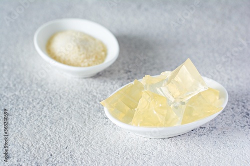 Gelatin, agar-agar, gelatinous mass (cubes in the form of crystals) on a gray background. Gelling agent (collagen) for culinary, confectionery products.