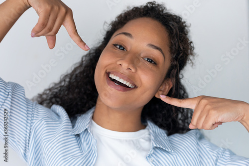 Tablou pe pânză Pretty young african american woman with perfect smile looking at camera with happy expression over white background