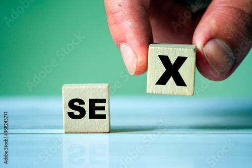 Symbol of SEX with word on wooden cube blocks. Hand hold one cube. Sex education or sexual issues topic.