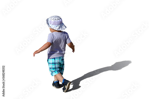 a small running child in a Panama hat and shorts with a shadow on a Sunny day