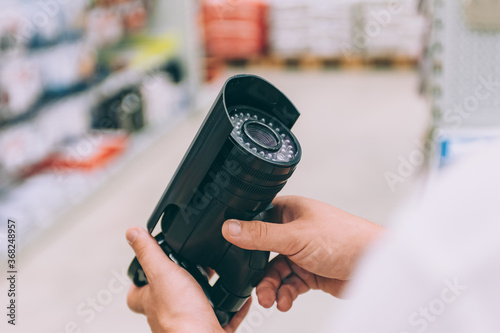 A man holds a street video camera in his hands. Concept man chooses a product in a store.