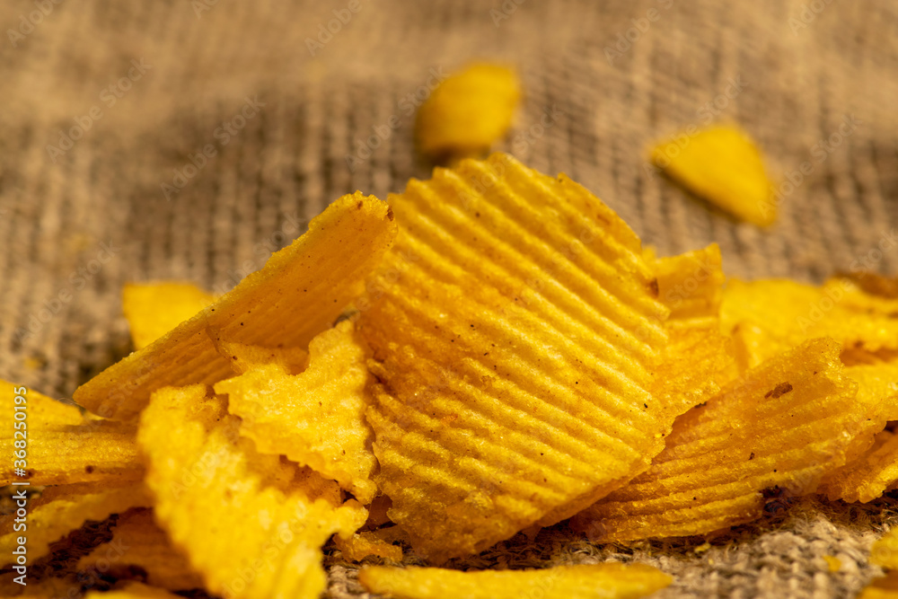 Fluted potato chips on a background of homespun fabric with a rough texture. Close up. Fluted potato chips on a background of homespun fabric with a rough texture. Close up.