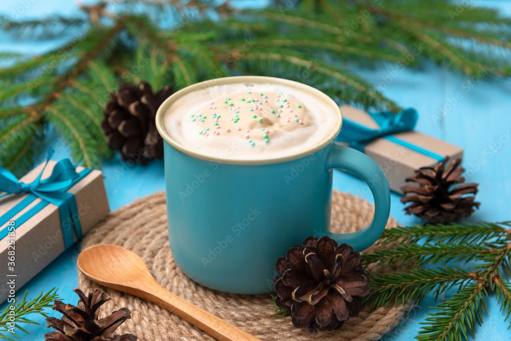 Fragrant delicious coffee on a light blue table with fir branches and cones