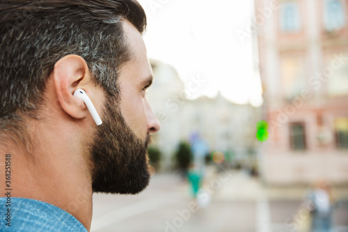 Confident young man wearing wireless earphones