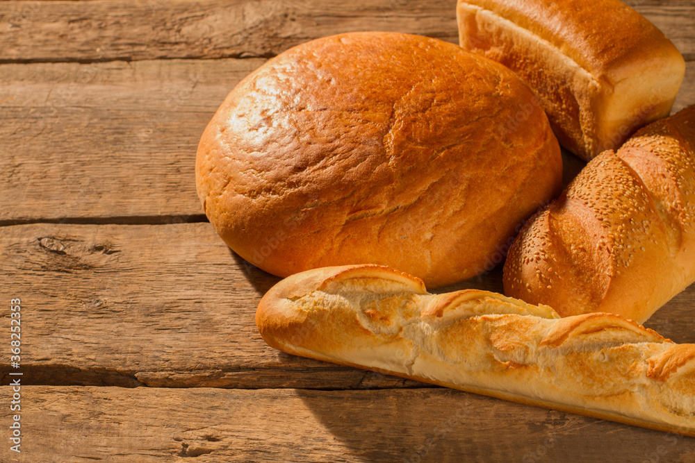 Assorted artisan bread on wooden background. Freshly baked bread with golden crust.