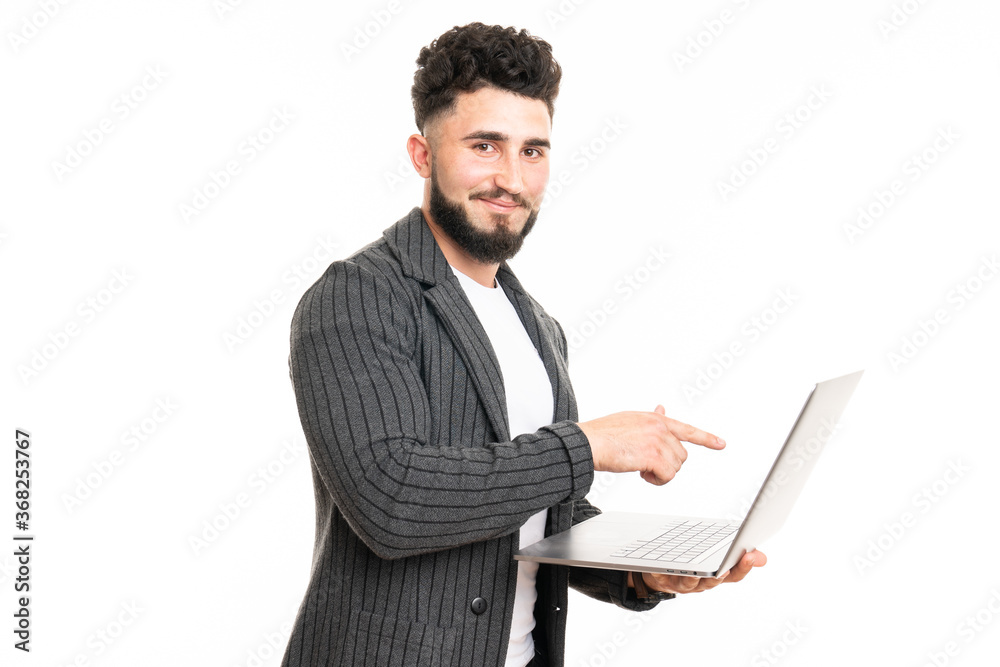 Working with joy. Handsome young man using his laptop and looking at camera with smile while standing against white background Working with joy. Handsome young man using his laptop and looking at camera with smile while standing against white background