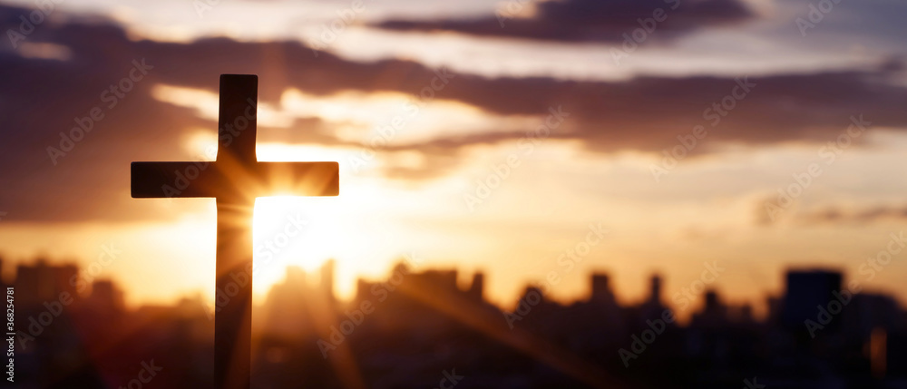 Silhouette cross against the sky At Sunset. Dramatic city background. Crucifixion Of Jesus Christ. Religion concept.