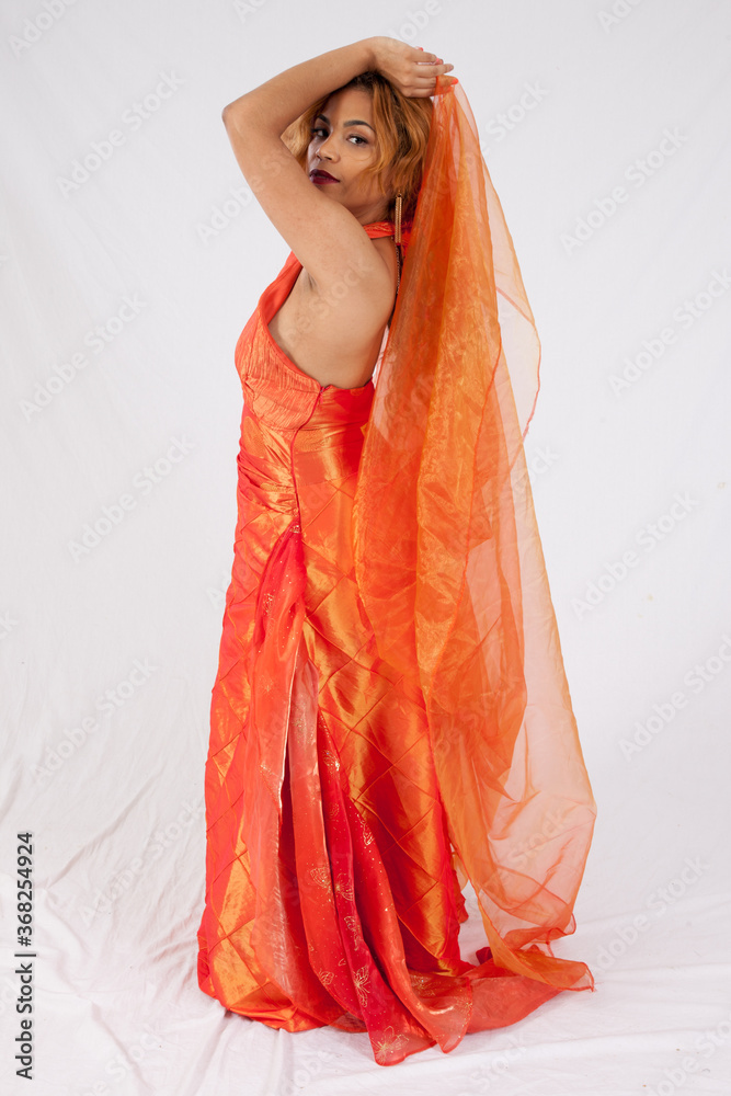 Pretty Hispanic woman playing with her flowing orange dress