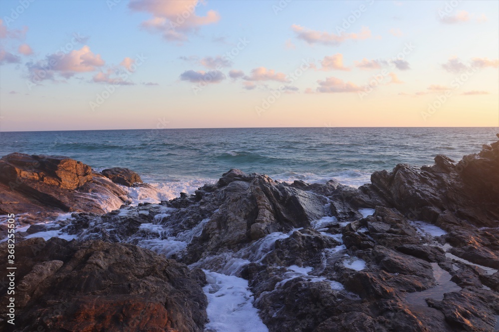 Sea water flowing down rocks with ocean and sunset in the background Sea water flowing down rocks with ocean and sunset in the background