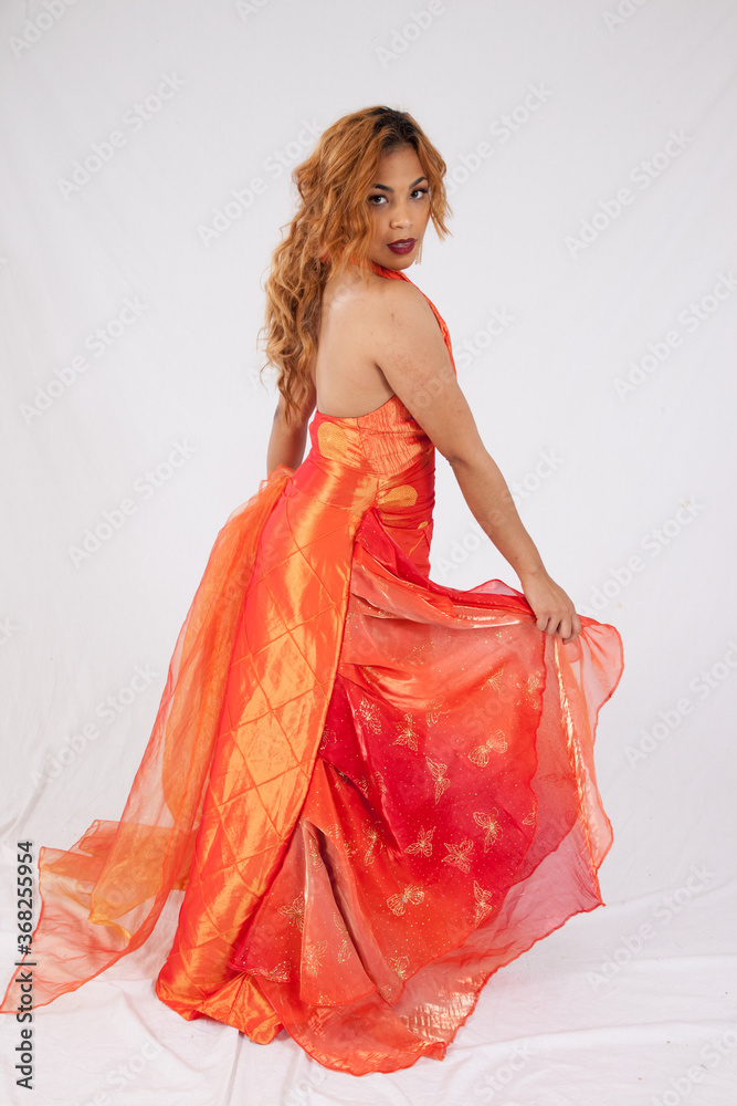 Pretty Hispanic woman playing with her flowing orange dress Pretty Hispanic woman playing with her flowing orange dress