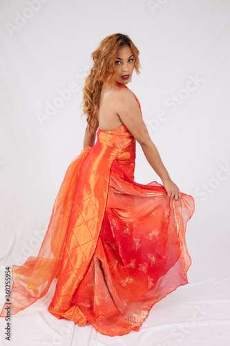 Pretty Hispanic woman playing with her flowing orange dress