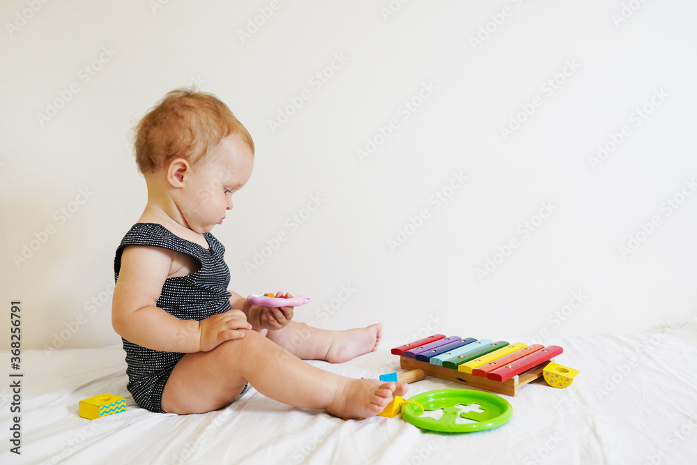 Cute baby girl playing with toys while sitting on bed. Smart funny child. Cute baby girl playing with toys while sitting on bed. Smart funny child.