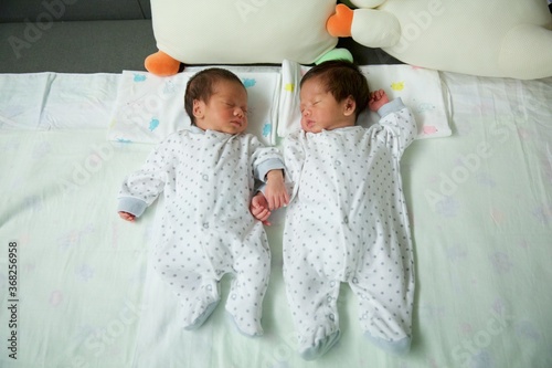 Cute twin baby asian boys sleeping together.