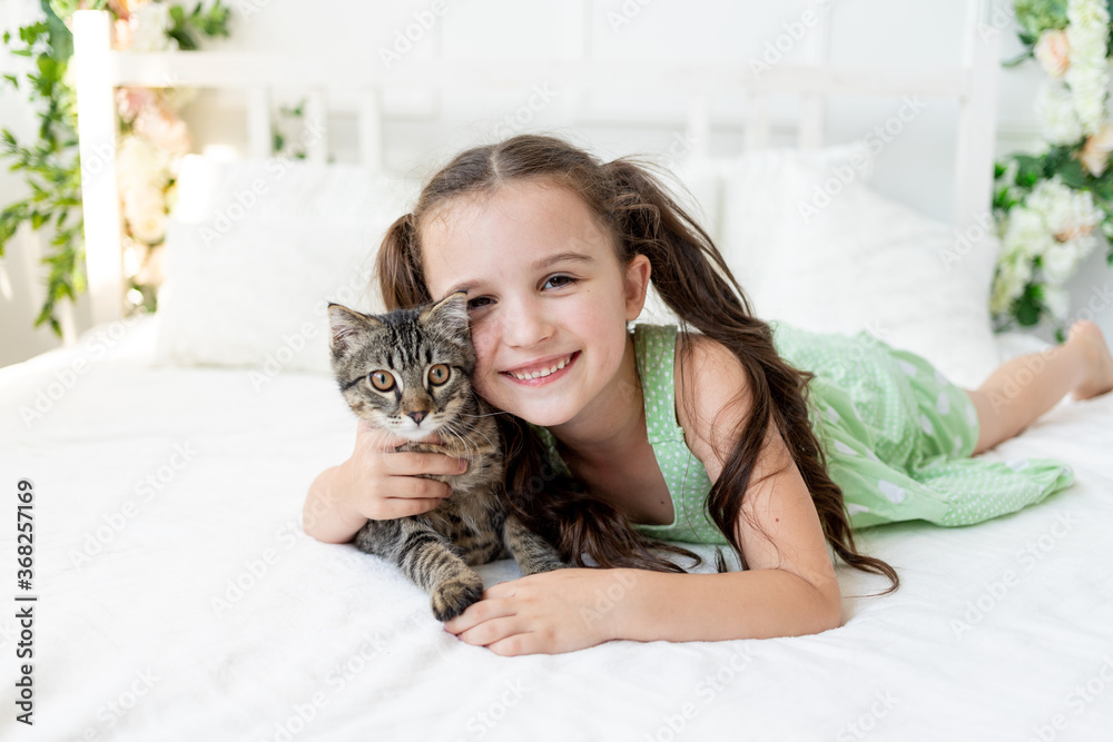 A child is torturing an animal, a little girl with a cat is lying on the bed, the concept of a child's friendship with animals A child is torturing an animal, a little girl with a cat is lying on the bed, the concept of a child's friendship with animals