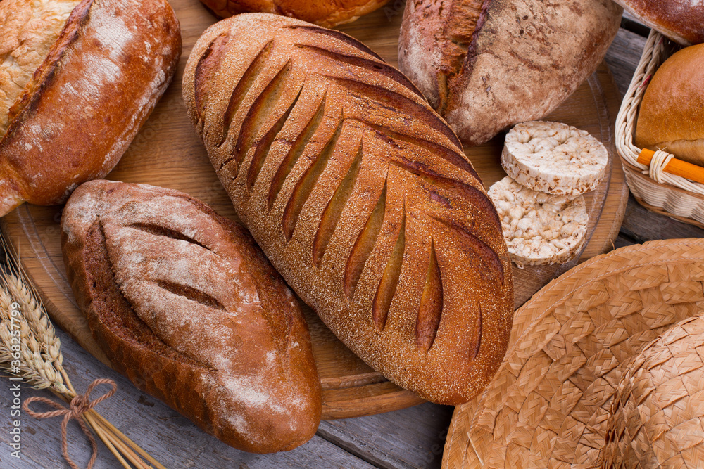 Assortment of baked bread on wooden table background. Fresh delicious bakery products background.