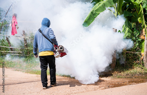Worker fogging machine spraying smoke to eliminate mosquitoes.