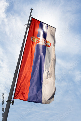 Flag of Serbia waving in the wind against white cloudy blue sky