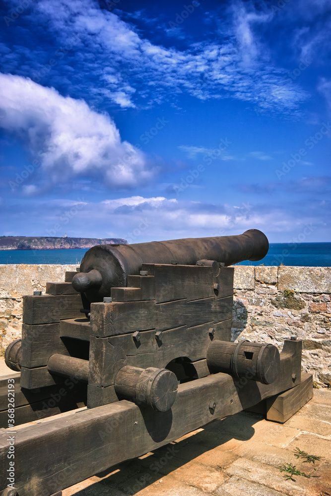Fort-La-Latte, Brittany, France. Cannon in the castle pointed towards the sea. Summer day, blue sky with beautiful clouds.