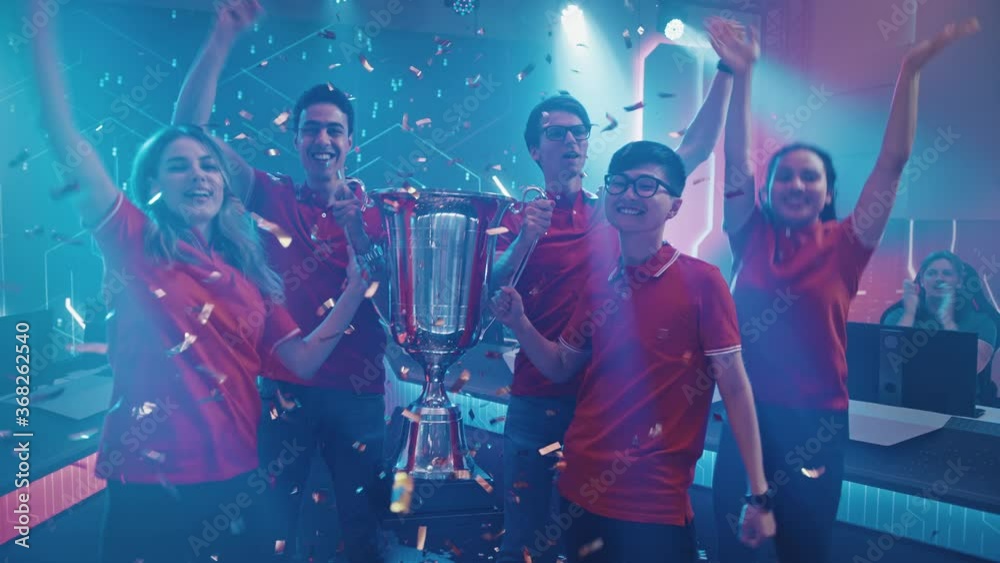 Diverse Esport Team Winner of the Video Games Tournament Celebrates Victory Cheering and Lifting Trophy in Big Championship Arena. Cyber Gaming Event with Gamers and Fans. Elevating Slow Motion Shot Diverse Esport Team Winner of the Video Games Tournament Celebrates Victory Cheering and Lifting Trophy in Big Championship Arena. Cyber Gaming Event with Gamers and Fans. Elevating Slow Motion Shot