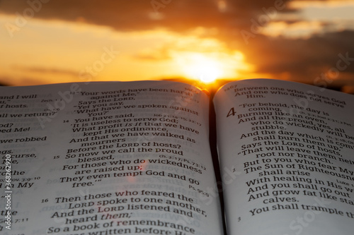 Holy Bible open at sunset with highlight on Malachi 4: 2. Background with clouds and sunbeams. photo