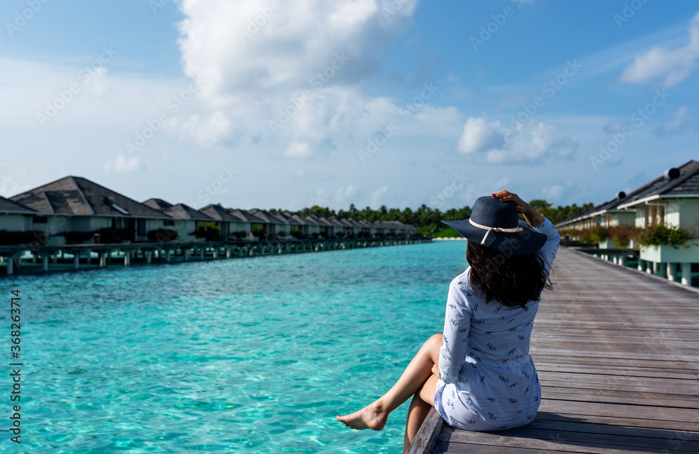 Young girl on travel vacation. Blue sea and white sand. Fashion girl enjoying on seashore.