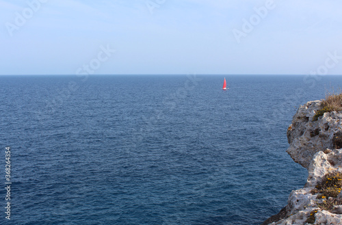 A boat with red sails sailing in the Mediterranean Sea. Selective focus in the foreground. Mallorca, Balearic Islands, Spain. © Alexander