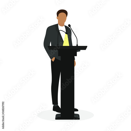 A man in a business suit stands at the stand with a microphone and a luminous lamp