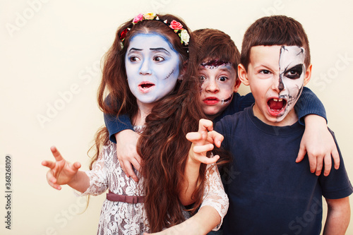 zombie apocalypse kids concept. Birthday party celebration facepaint on children dead bride, scar face, zombie skeleton together closeup makeup emotional posing. © iordani