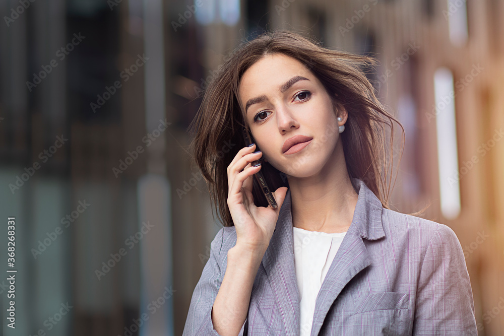Young, confident woman talking on a mobile smartphone. The female is formally dressed, a business woman speaks on a mobile phone. Copy Space