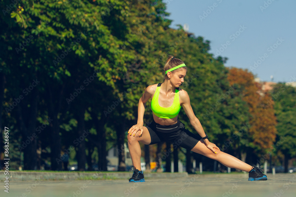 Stretching. Female runner, athlete training outdoors. Professional runner, jogger working out on the street. Concept of healthy lifestyle, sport, wellness, wellbeing, motion and action, activity. Stretching. Female runner, athlete training outdoors. Professional runner, jogger working out on the street. Concept of healthy lifestyle, sport, wellness, wellbeing, motion and action, activity.