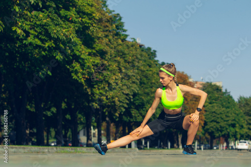 Stretching. Female runner, athlete training outdoors. Professional runner, jogger working out on the street. Concept of healthy lifestyle, sport, wellness, wellbeing, motion and action, activity. © master1305