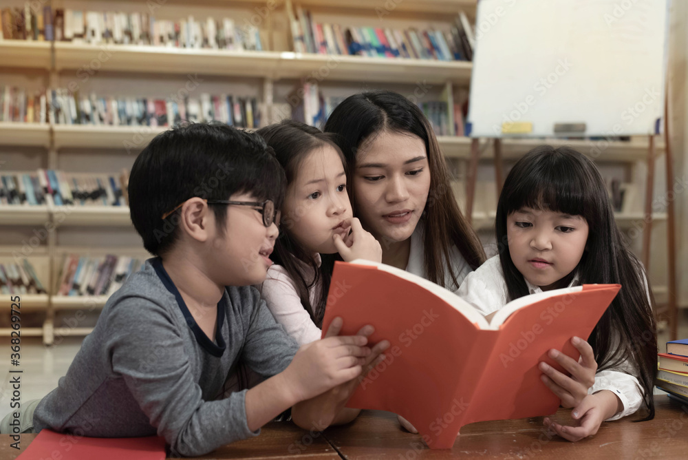 The beautiful lady reading book with three children with happy feeling,blurry light around The beautiful lady reading book with three children with happy feeling,blurry light around