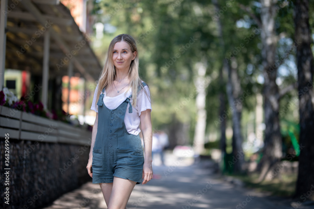 girl in overalls walks in the summer on the street girl in overalls walks in the summer on the street