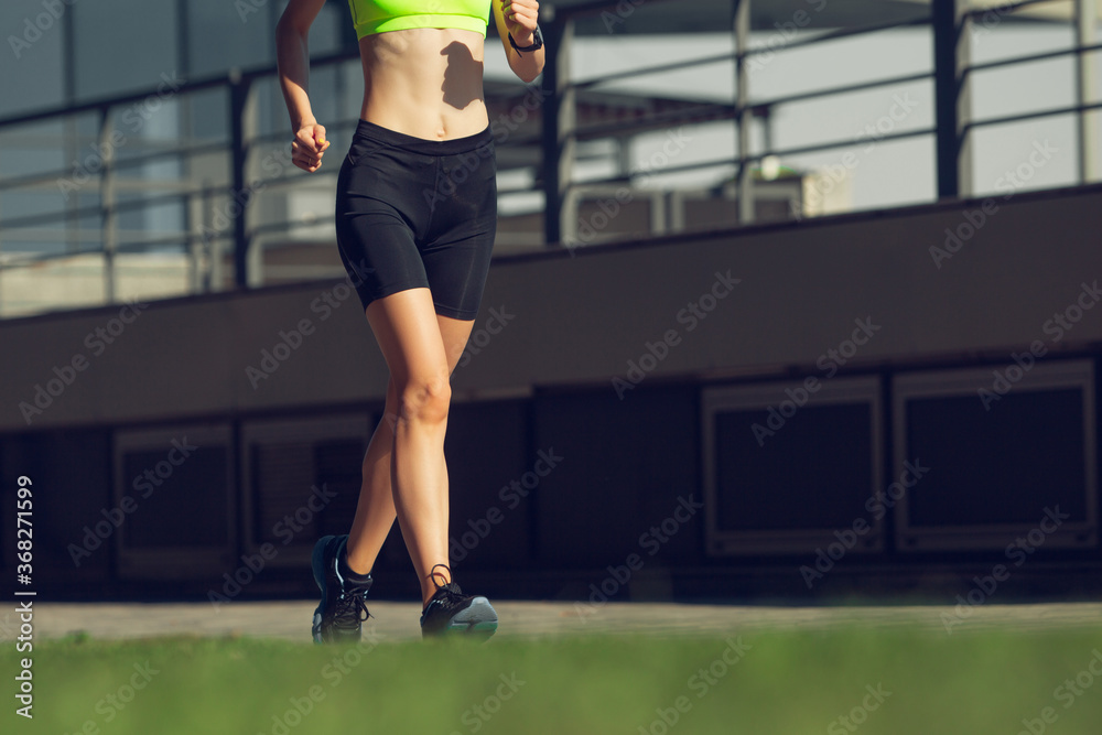 Strong. Female runner, athlete training outdoors. Professional runner, jogger working out on the street. Concept of healthy lifestyle, sport, wellness, wellbeing, motion and action, activity.