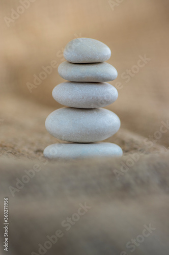 One simplicity stones cairn on jute brown background  group of five light gray pebbles built in tower